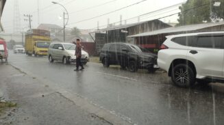 Diguyur Hujan Deras, Kapolsek Blangpidie Tetap Berdiri Atur Kemacetan di Jalan Irian