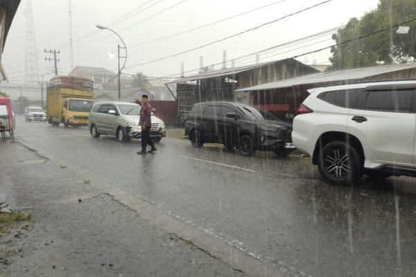 Diguyur Hujan Deras, Kapolsek Blangpidie Tetap Berdiri Atur Kemacetan di Jalan Irian