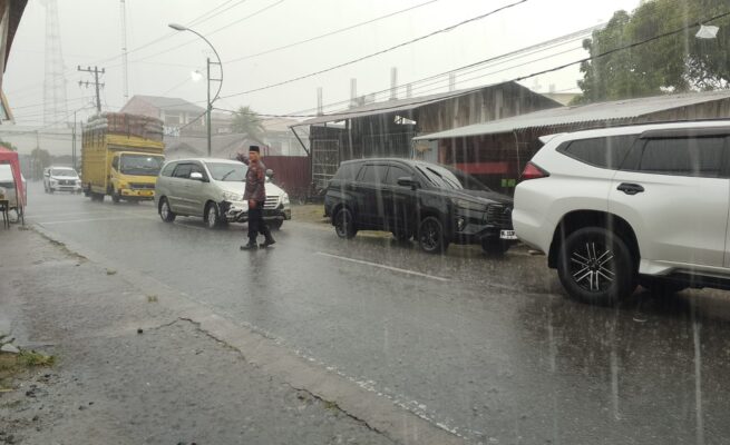 Diguyur Hujan Deras, Kapolsek Blangpidie Tetap Berdiri Atur Kemacetan di Jalan Irian